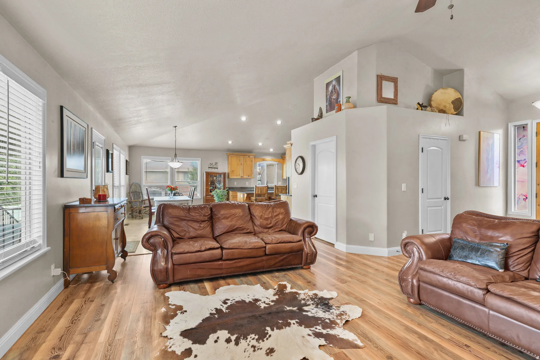 Vaulted ceilings with recessed lighting, wood-finish flooring, multiple windows with blinds, and white interior doors