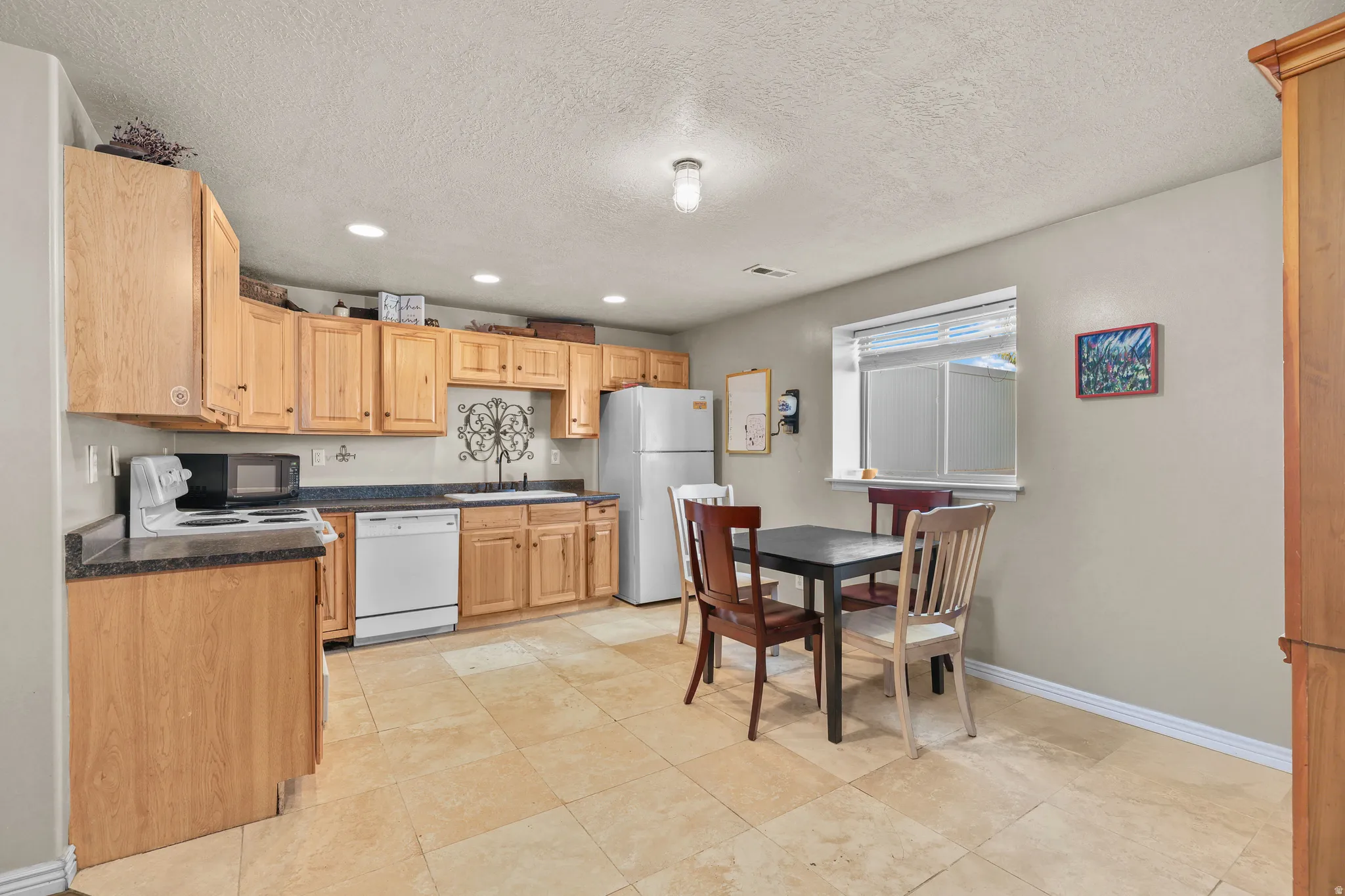 Kitchen featuring wood cabinetry, a built-in dishwasher, an electric range, and a tile floor