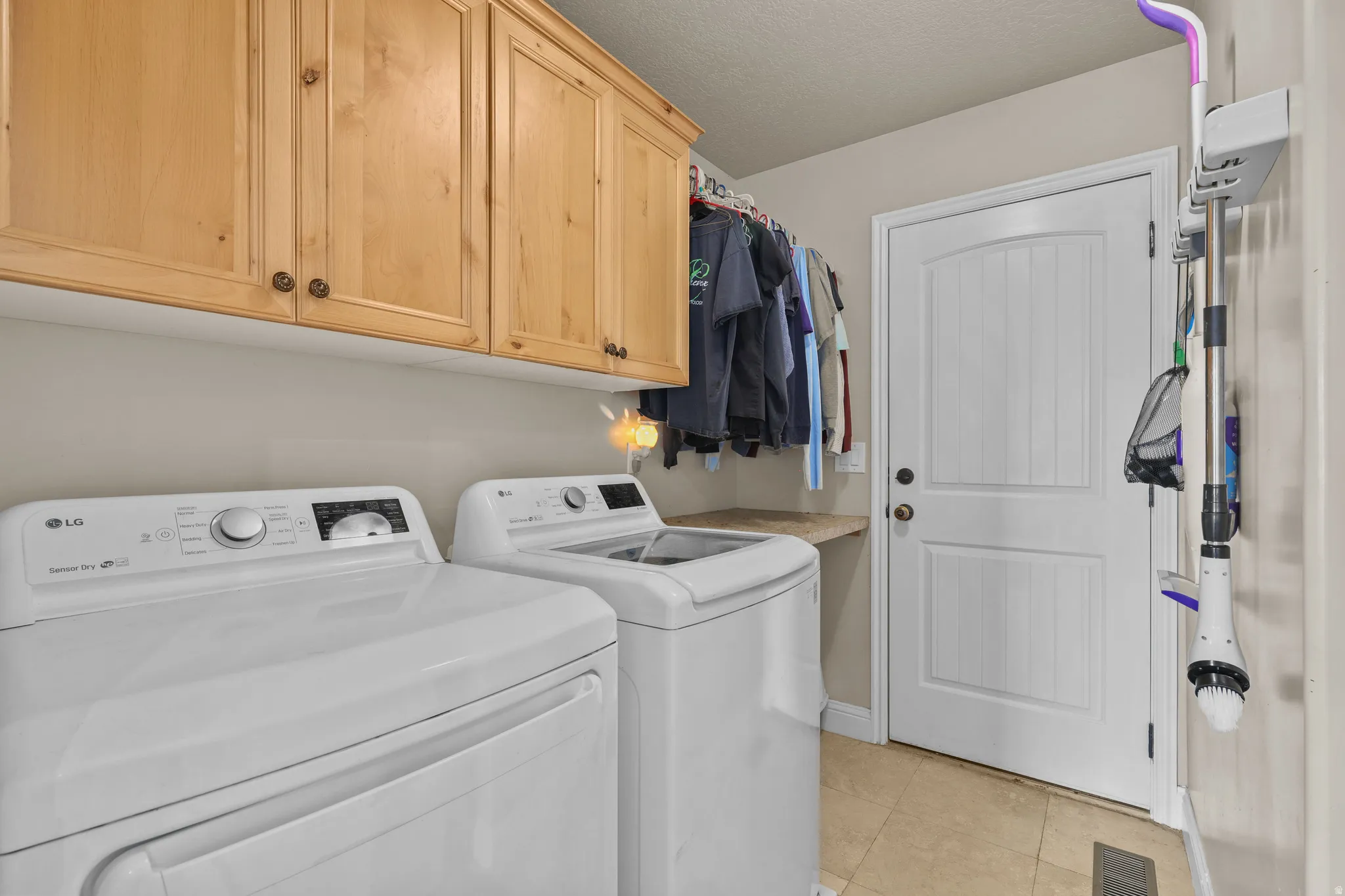 Laundry area featuring light wood cabinetry, a built-in counter, and tile flooring