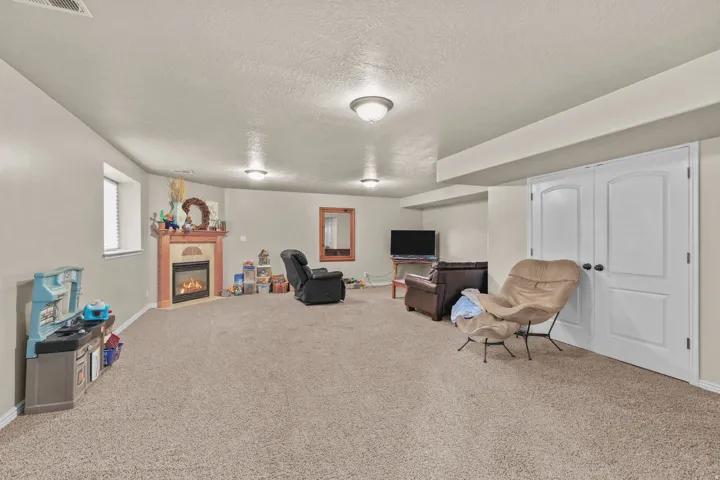Recessed corner fireplace with a mantel, carpeted flooring, and an egress window