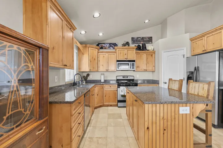 Kitchen featuring wood cabinetry, an island with countertop seating, stainless steel appliances, recessed lighting, and tile flooring