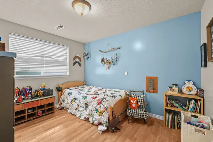 Wood-finish flooring, single window with blinds, ceiling-mounted light fixture, light blue wall accent