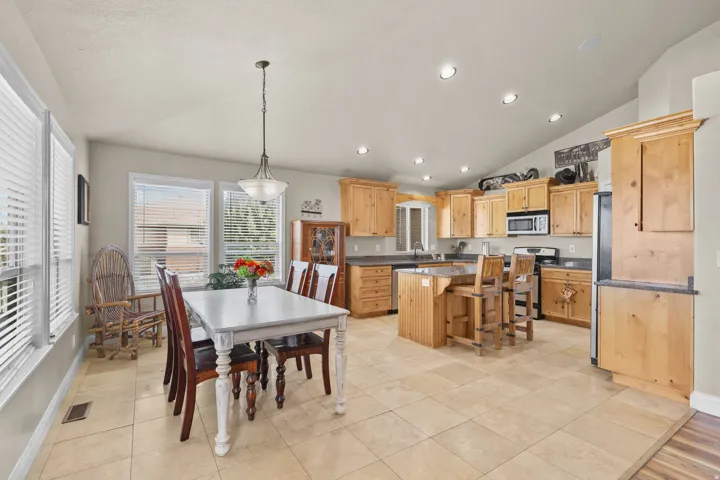 Open-concept kitchen and dining area featuring light-toned cabinetry, stainless steel appliances, and a central island with seating