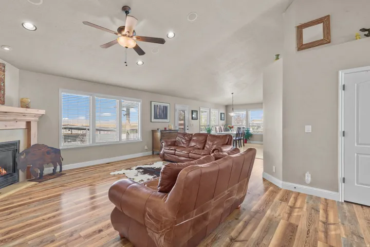 Spacious living area featuring wood-finish flooring, a fireplace with a wood mantle, and multiple windows providing ample natural light