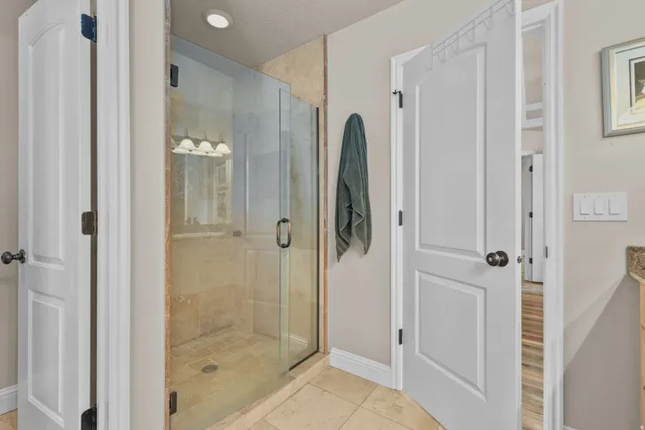 Glass-enclosed shower with a tiled interior and recessed lighting