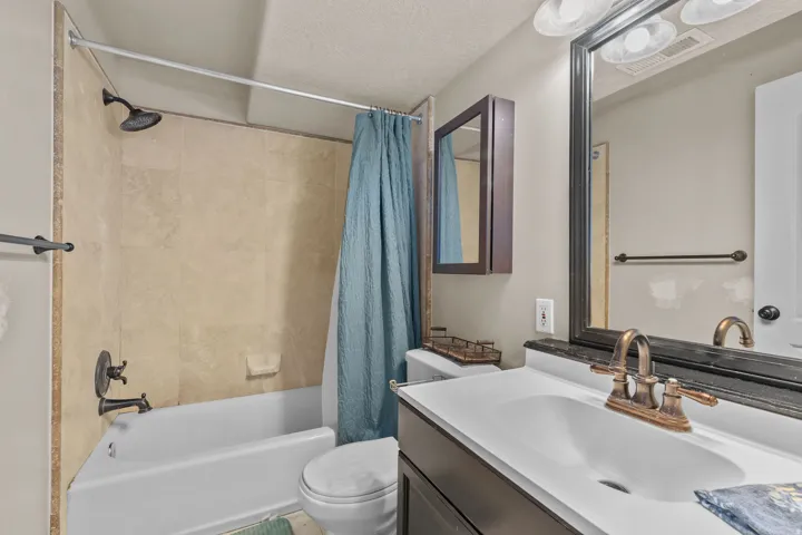 Bathroom featuring a shower-tub combination, wall-mounted vanity, framed mirror, and built-in medicine cabinet