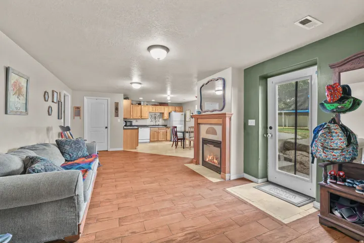 Wood-finish flooring throughout, featuring a built-in fireplace with a wood mantle, recessed lighting, and a kitchen with wood cabinetry and a tile backsplash