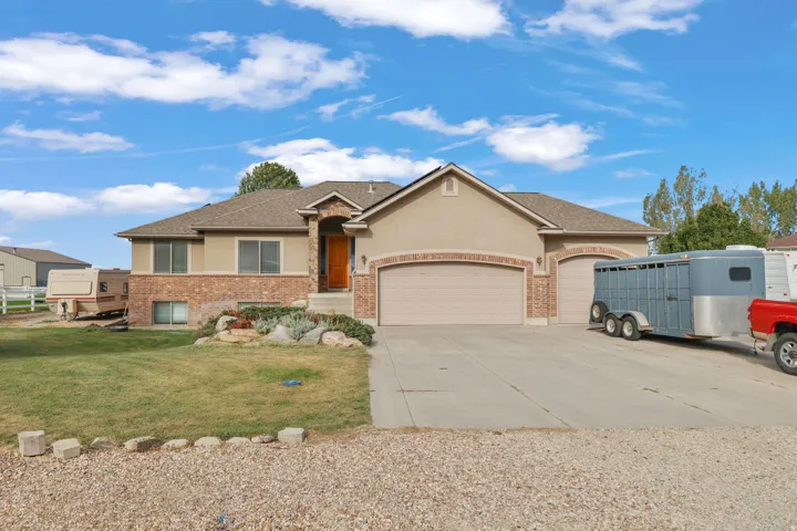 Stucco and brick facade with a two-car garage, concrete driveway, and front lawn