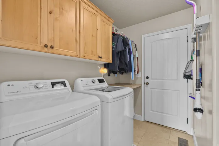 Laundry area featuring light wood cabinetry, a built-in counter, and tile flooring