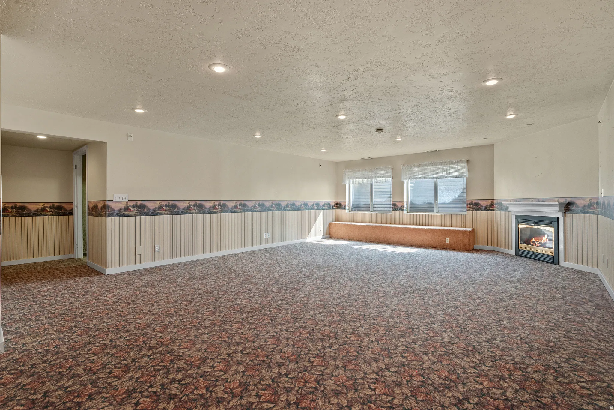 Spacious room featuring patterned carpet flooring, recessed lighting, and a built-in window bench