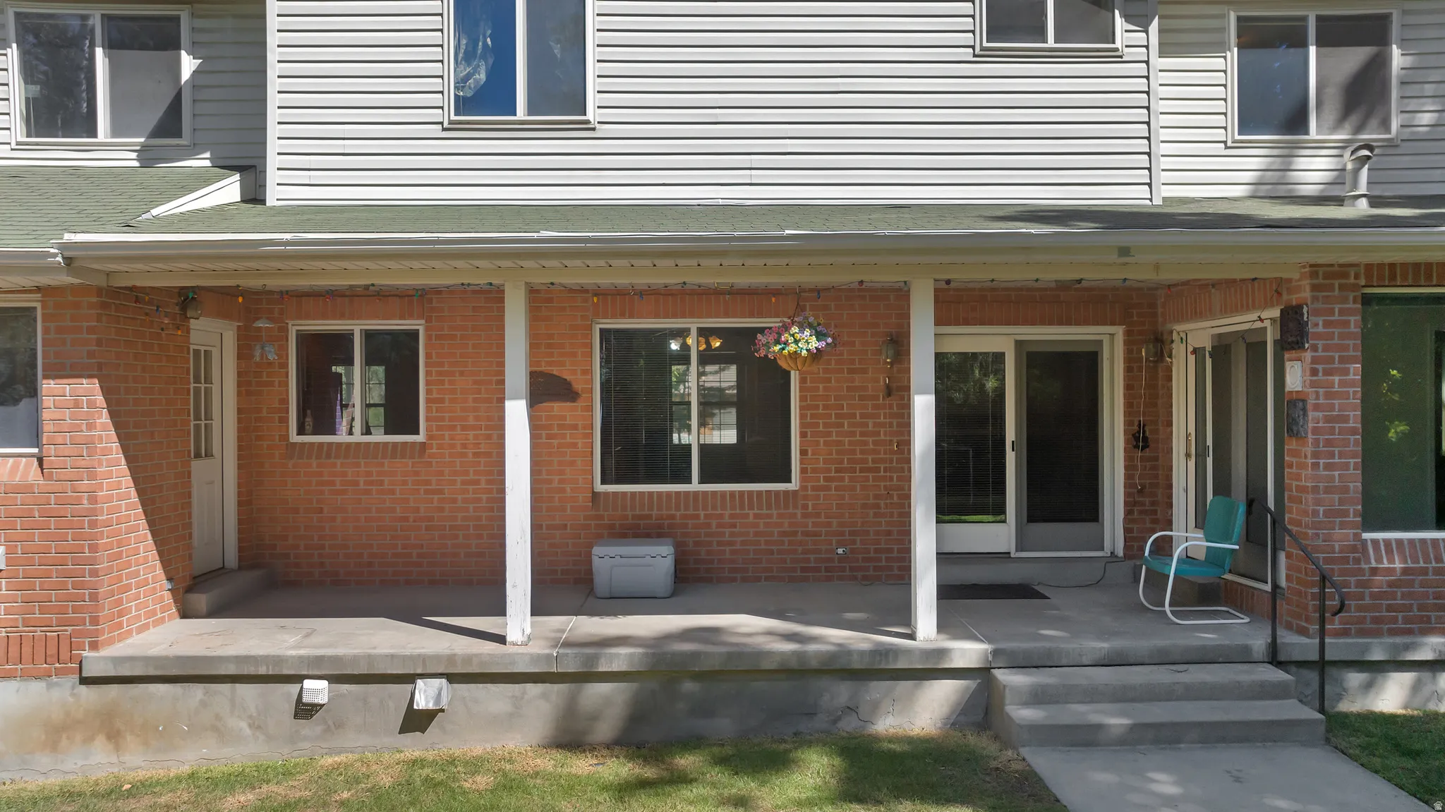 Brick and siding exterior with a covered porch, multiple windows, and a sliding glass door