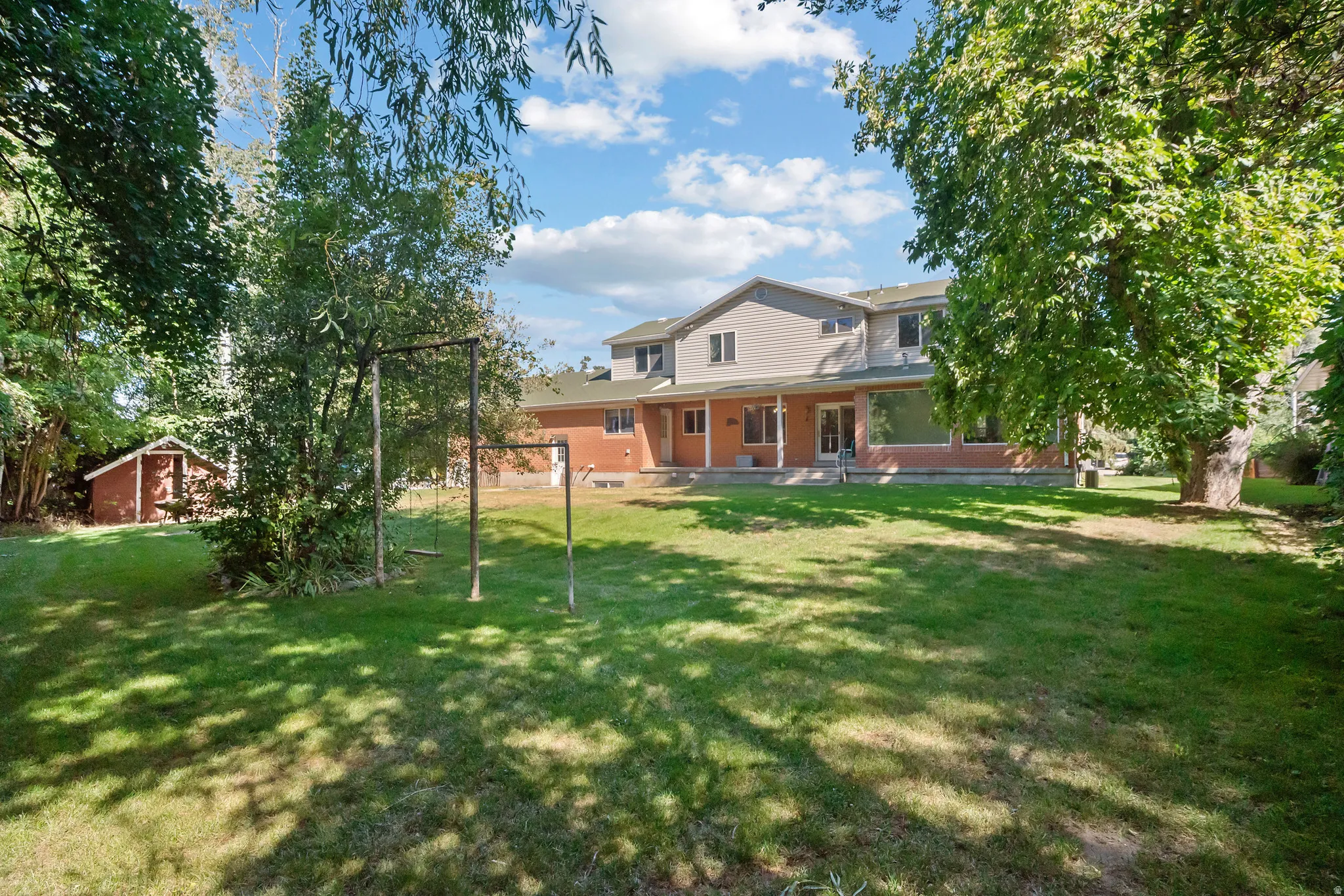 Expansive green lawn with mature trees and a detached storage shed
