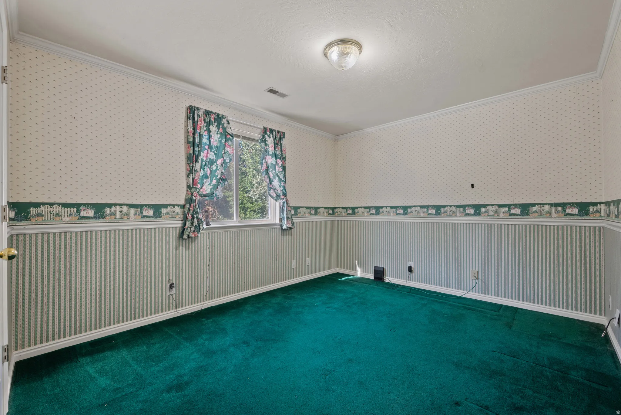 Crown molding, flush mount ceiling light, wall-to-wall carpeting, window with outdoor scenery, and wallpaper with chair rail detail