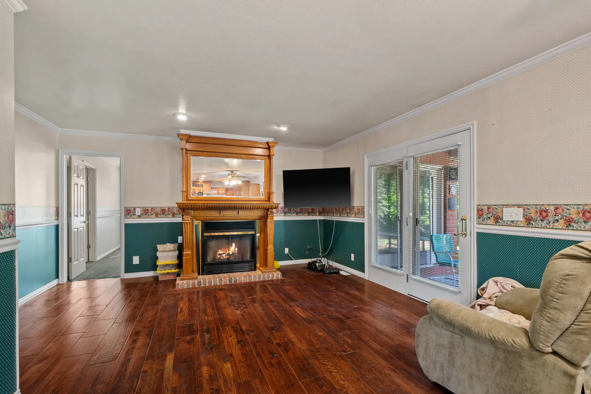 Wood-finish flooring, a brick-surround fireplace with a wood mantel, recessed lighting, and sliding glass doors