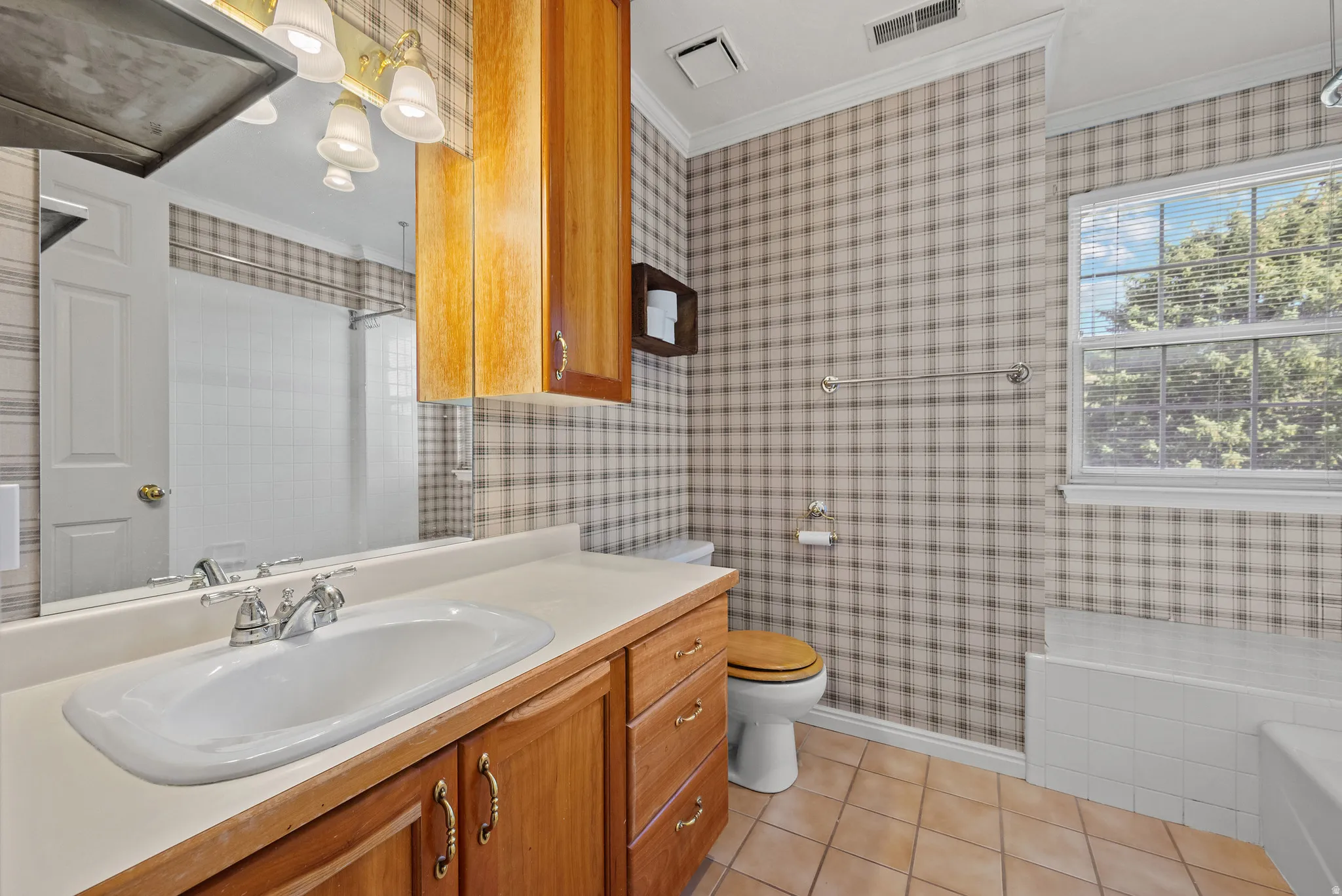 Wood-finish vanity with an integrated sink, polished chrome faucet, and overhead wood-finish cabinetry