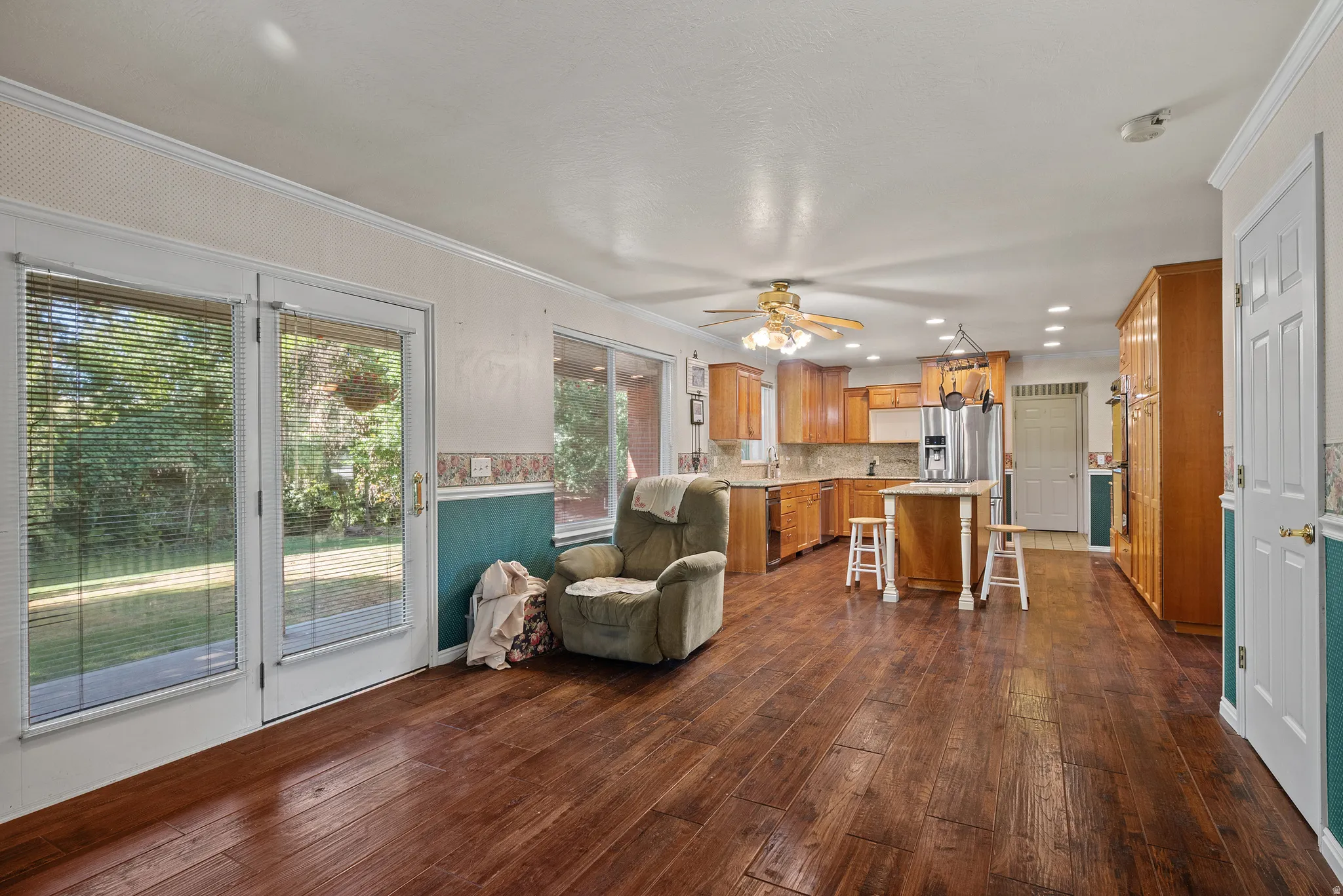Wood-finish flooring, glass panel doors, recessed lighting, ceiling fan, and wood cabinetry