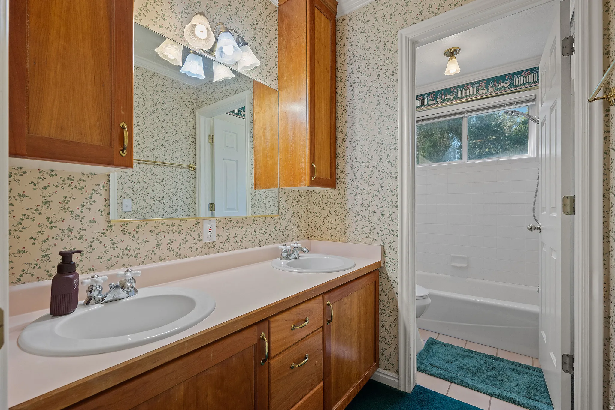 Dual vanity with integrated sinks, wood-finish cabinetry, and overhead lighting