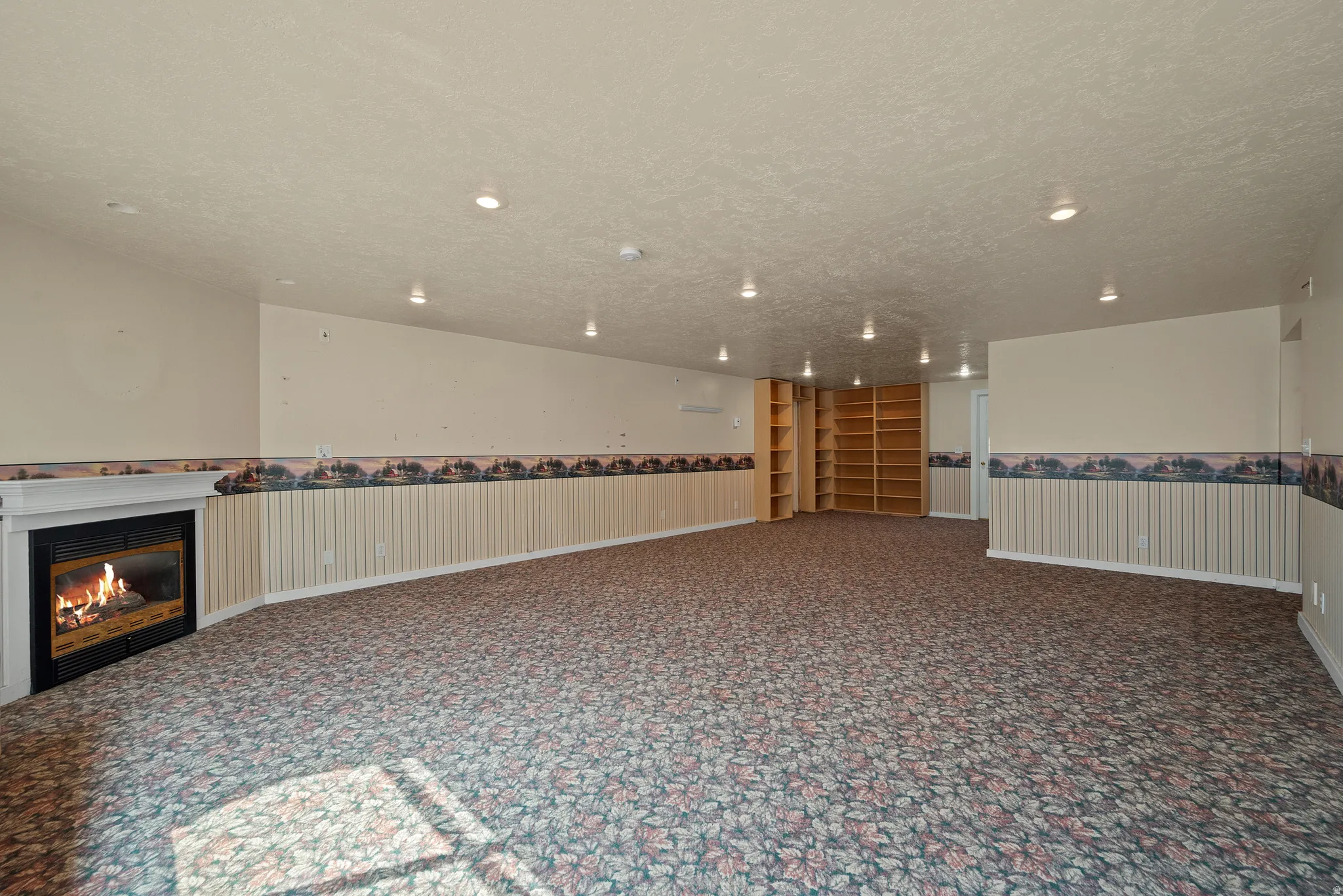Recessed ceiling lighting, built-in shelving, wainscoting, and a fireplace with a white mantel