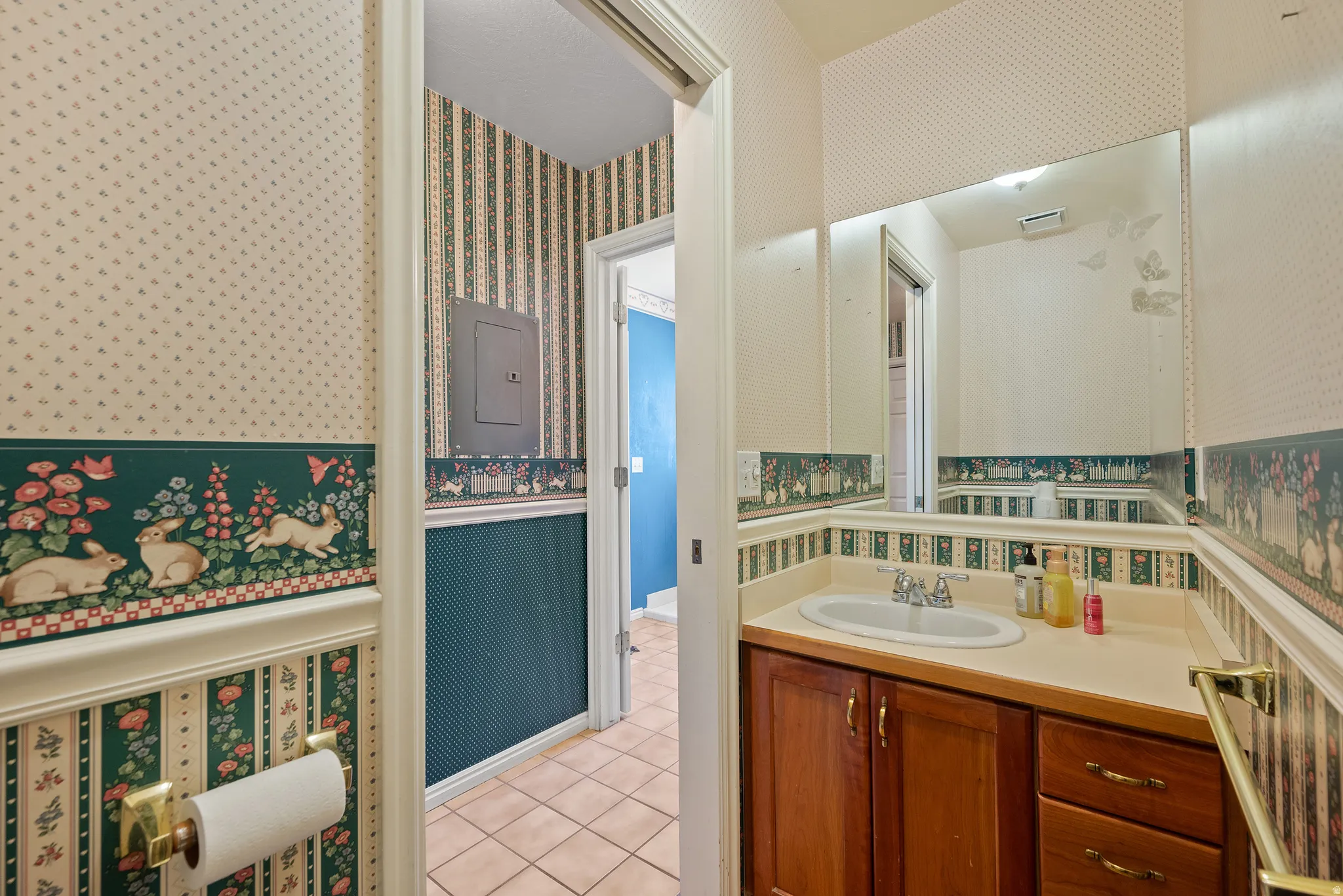 Vanity with a built-in sink and wood-finish cabinetry, a wall-mounted mirror, and tile flooring