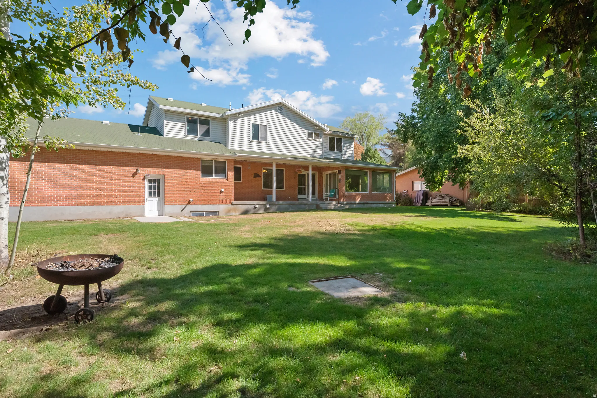 Expansive green lawn with mature trees and a brick and siding exterior