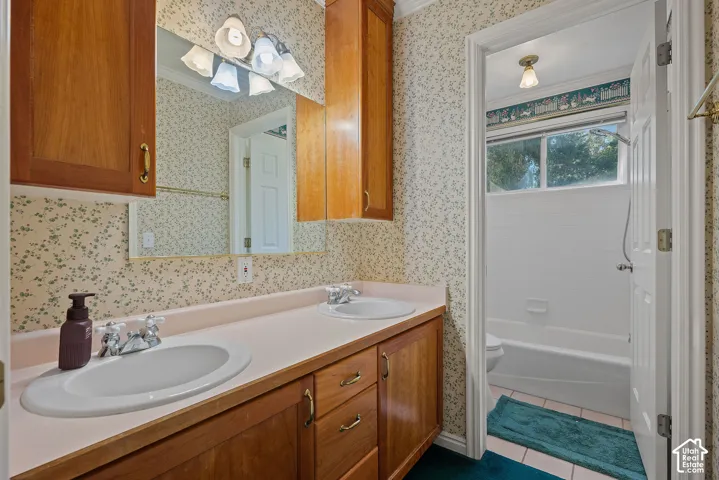 Dual vanity with integrated sinks, wood-finish cabinetry, and overhead lighting