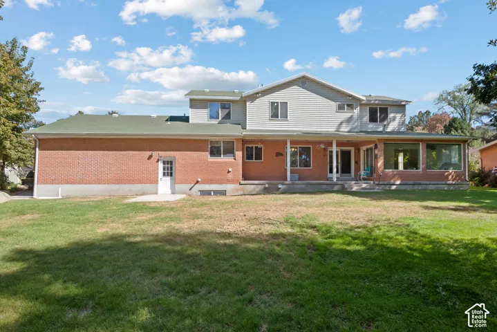 Two-story residence featuring a brick and siding exterior, expansive rear yard, covered porch, and a sunroom with large windows