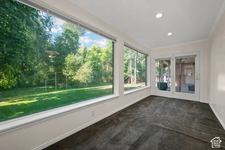 Expansive full-height windows, dark gray carpeting, recessed ceiling lighting, crown molding, and double glass-paneled doors