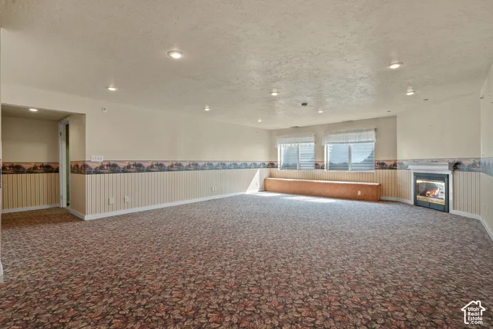 Spacious room featuring patterned carpet flooring, recessed lighting, and a built-in window bench