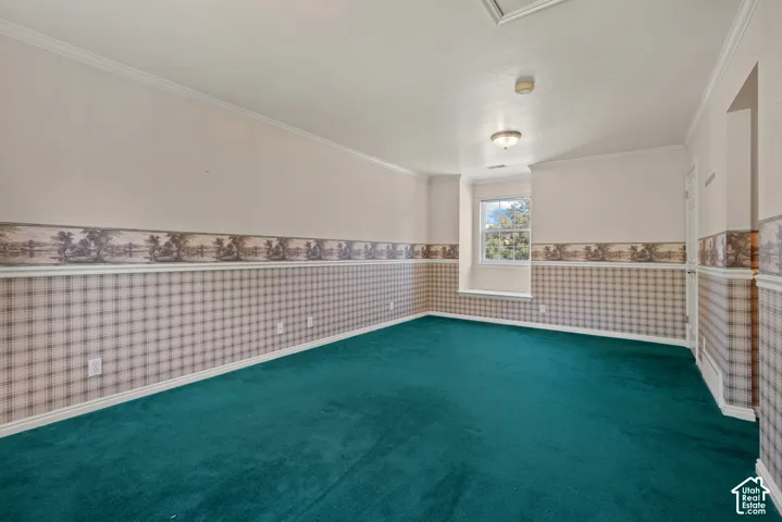 Spacious room featuring broadloom carpeting, a window, wall sconce, and crown molding