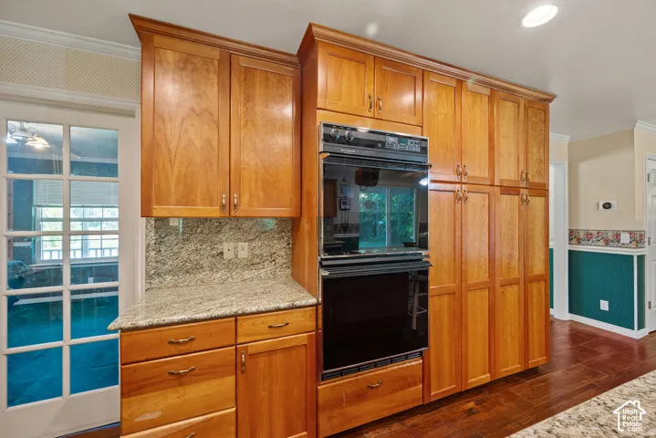 Built-in double oven, extensive cabinetry with wood finishes, granite countertops, and wood-finish flooring
