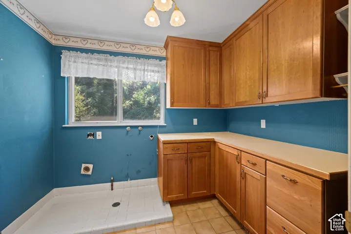 Built-in cabinetry with wood-finish doors, ample countertop space, a window, overhead lighting, and tile flooring