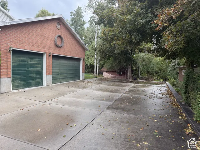 Brick exterior garage with two green doors and a concrete driveway