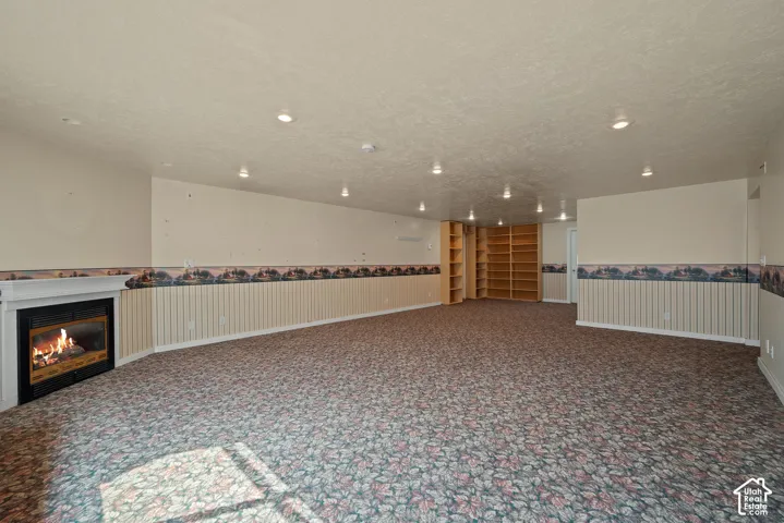 Recessed ceiling lighting, built-in shelving, wainscoting, and a fireplace with a white mantel