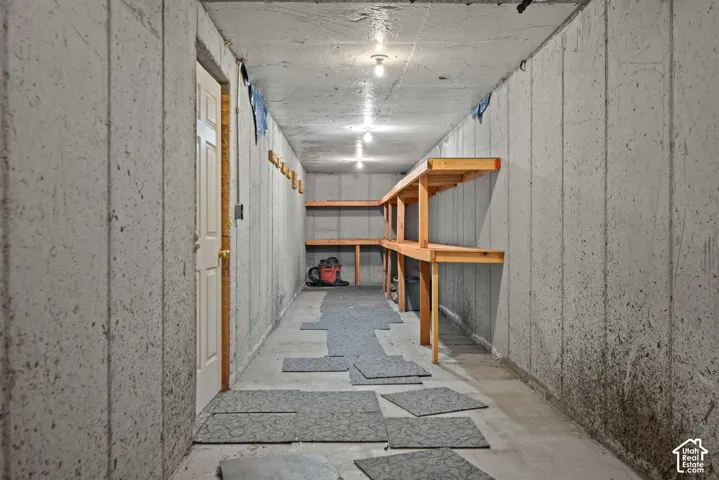 Concrete wall construction with built-in wooden shelving, recessed ceiling lighting, and a white paneled door