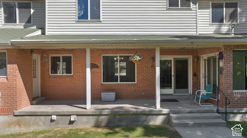 Brick and siding exterior with a covered porch, multiple windows, and a sliding glass door