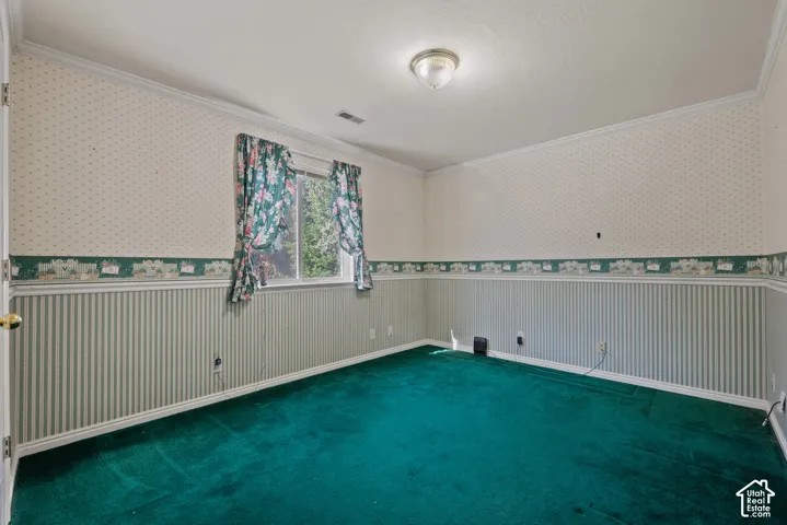 Crown molding, flush mount ceiling light, wall-to-wall carpeting, window with outdoor scenery, and wallpaper with chair rail detail