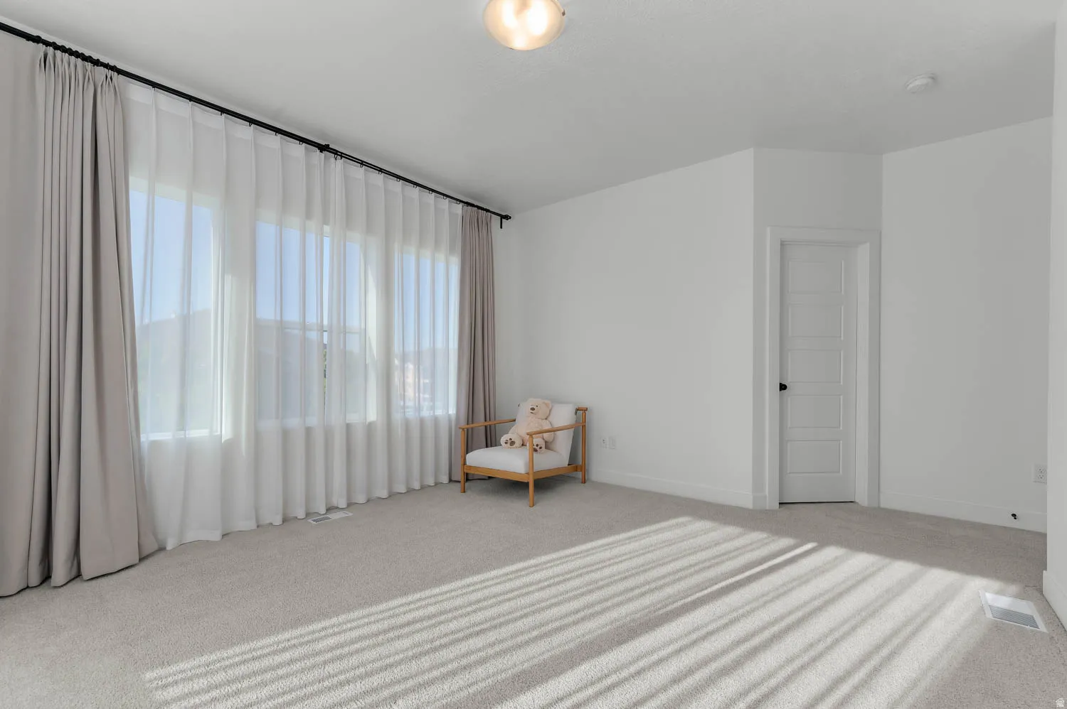 Expansive room featuring light-toned carpeting and white walls
