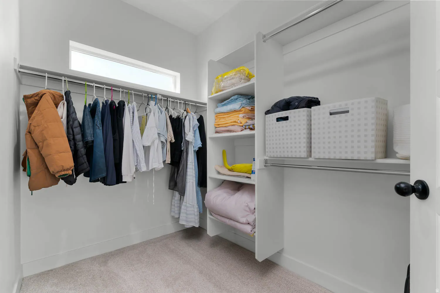 Custom closet organization system with built-in shelving, multiple hanging rods, and carpet flooring