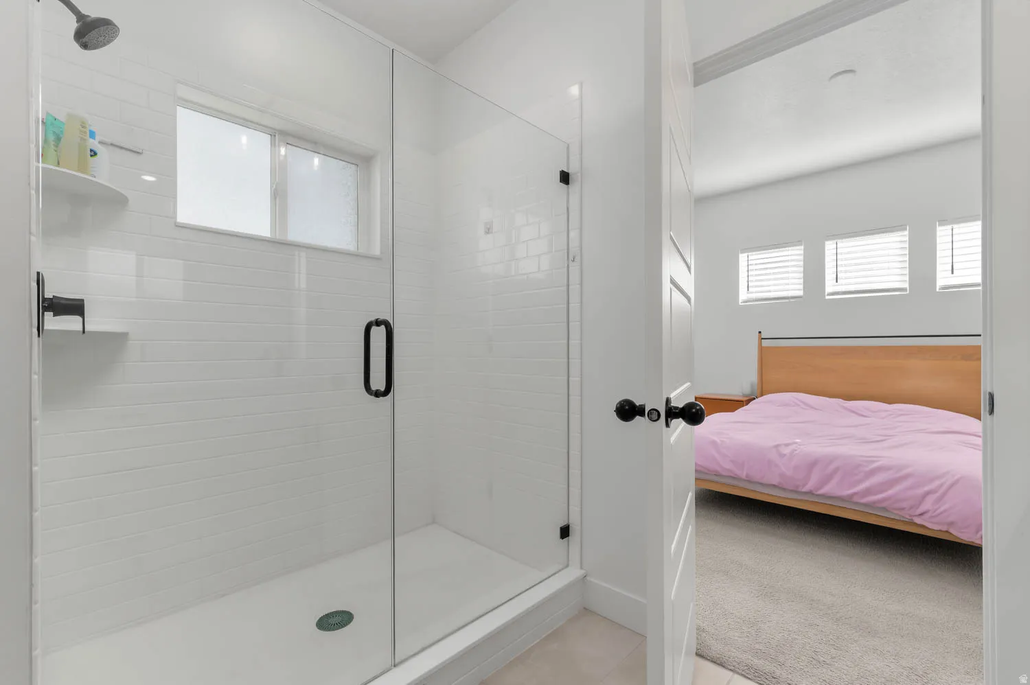 Glass-enclosed shower with white subway tile, a built-in shower shelf, and a rainfall showerhead