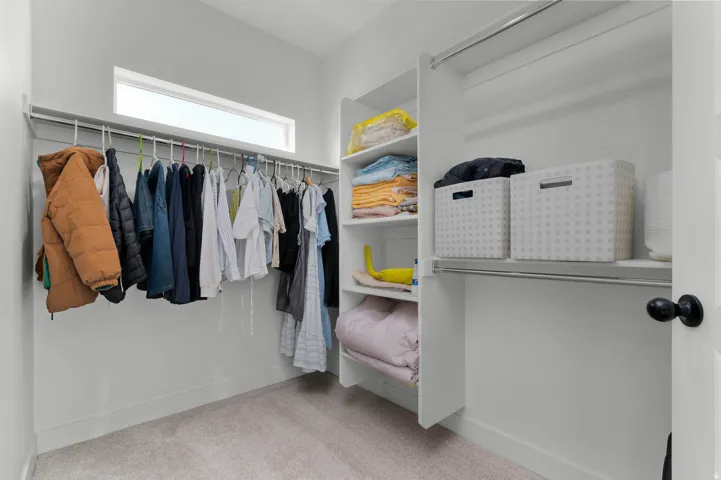 Custom closet organization system with built-in shelving, multiple hanging rods, and carpet flooring