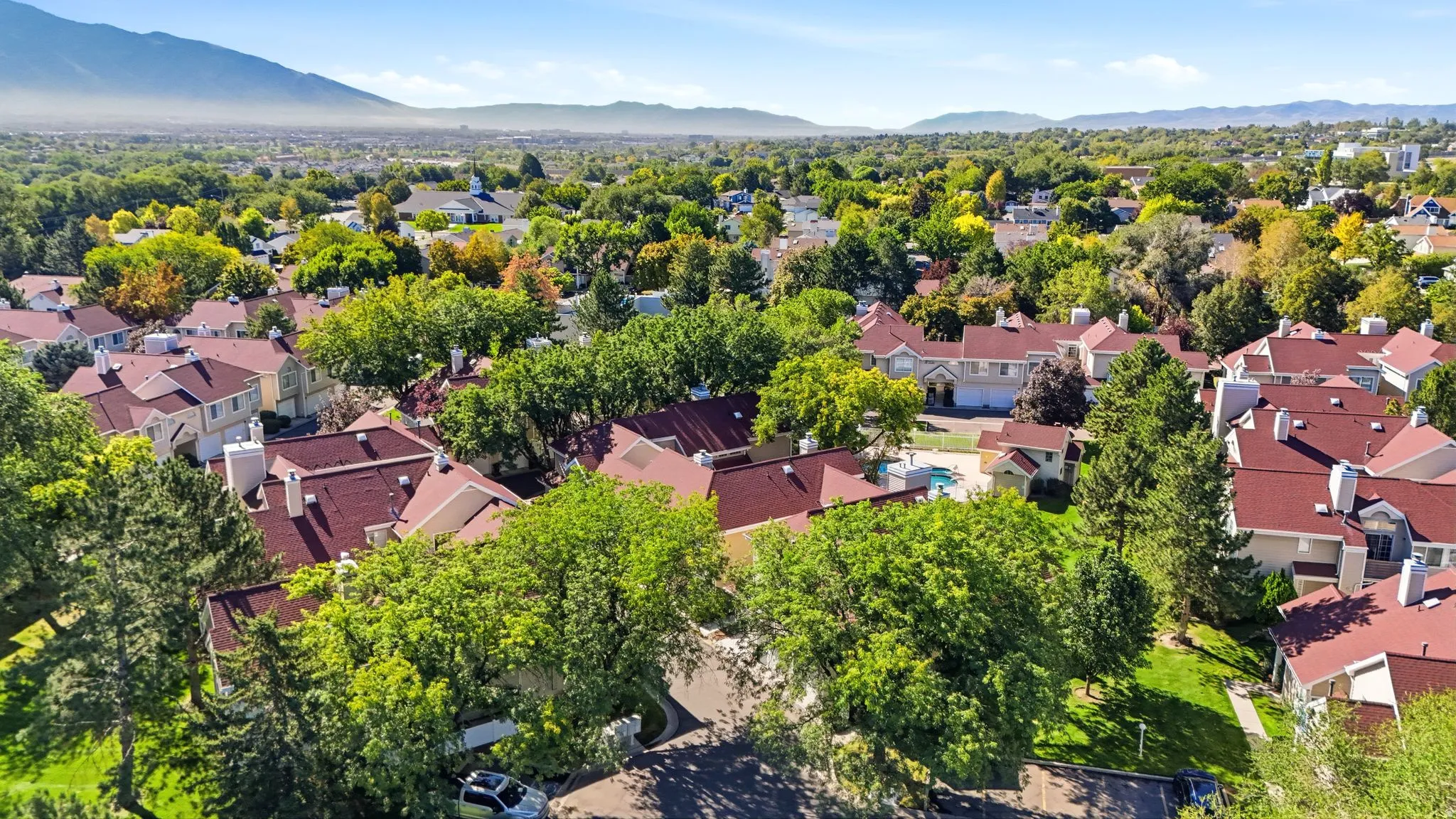 Community with mature trees, red-tiled roofs, and a swimming pool