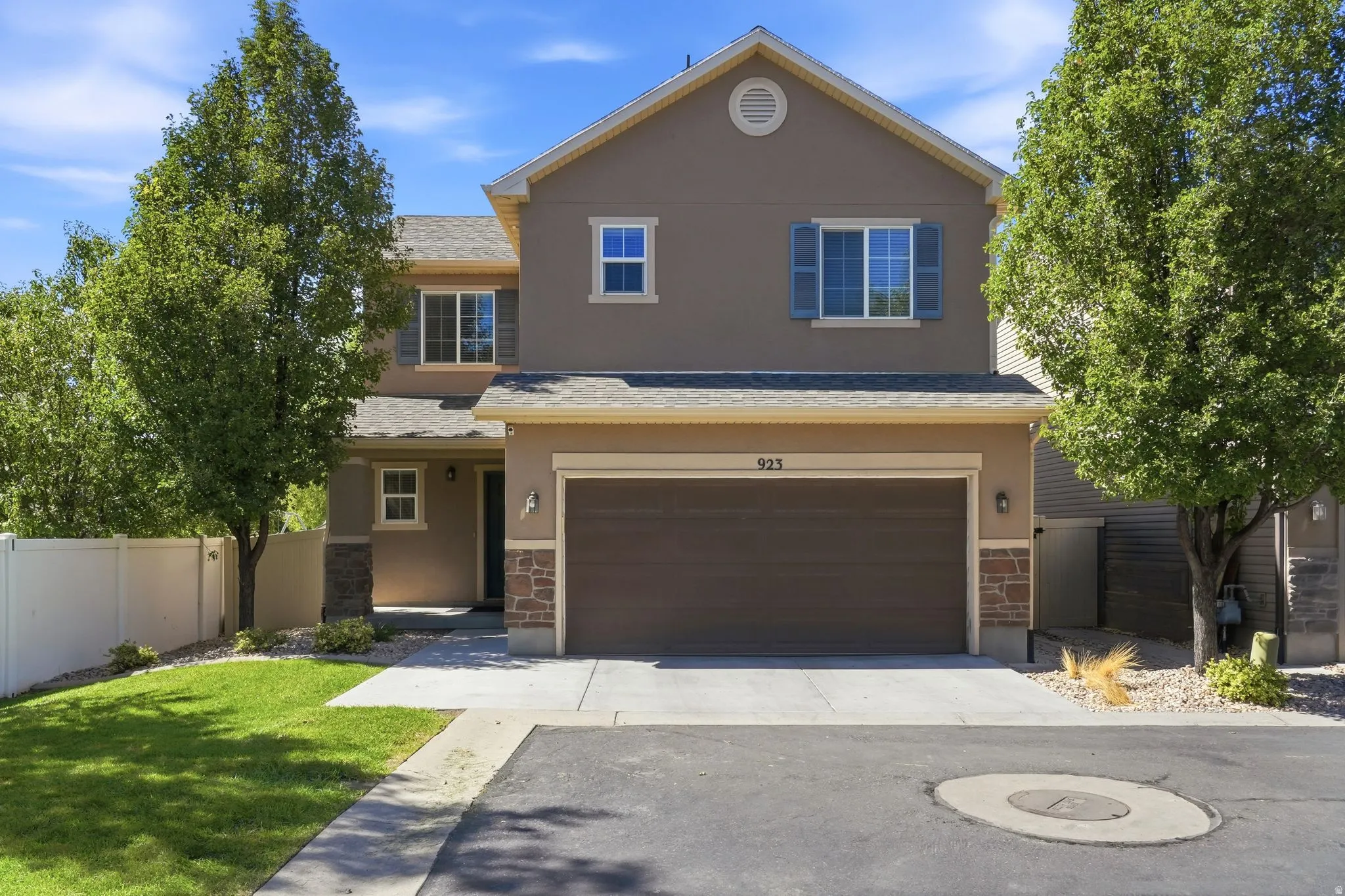 Stucco exterior with stone accents, attached two-car garage, covered entry, and a paved driveway
