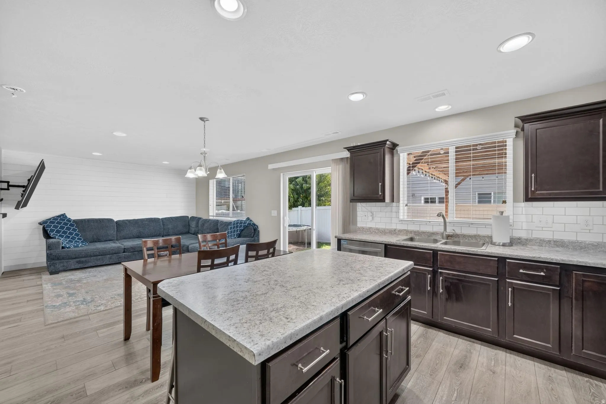 Open-concept living space featuring wood-finish flooring, recessed lighting, and a shiplap accent wall