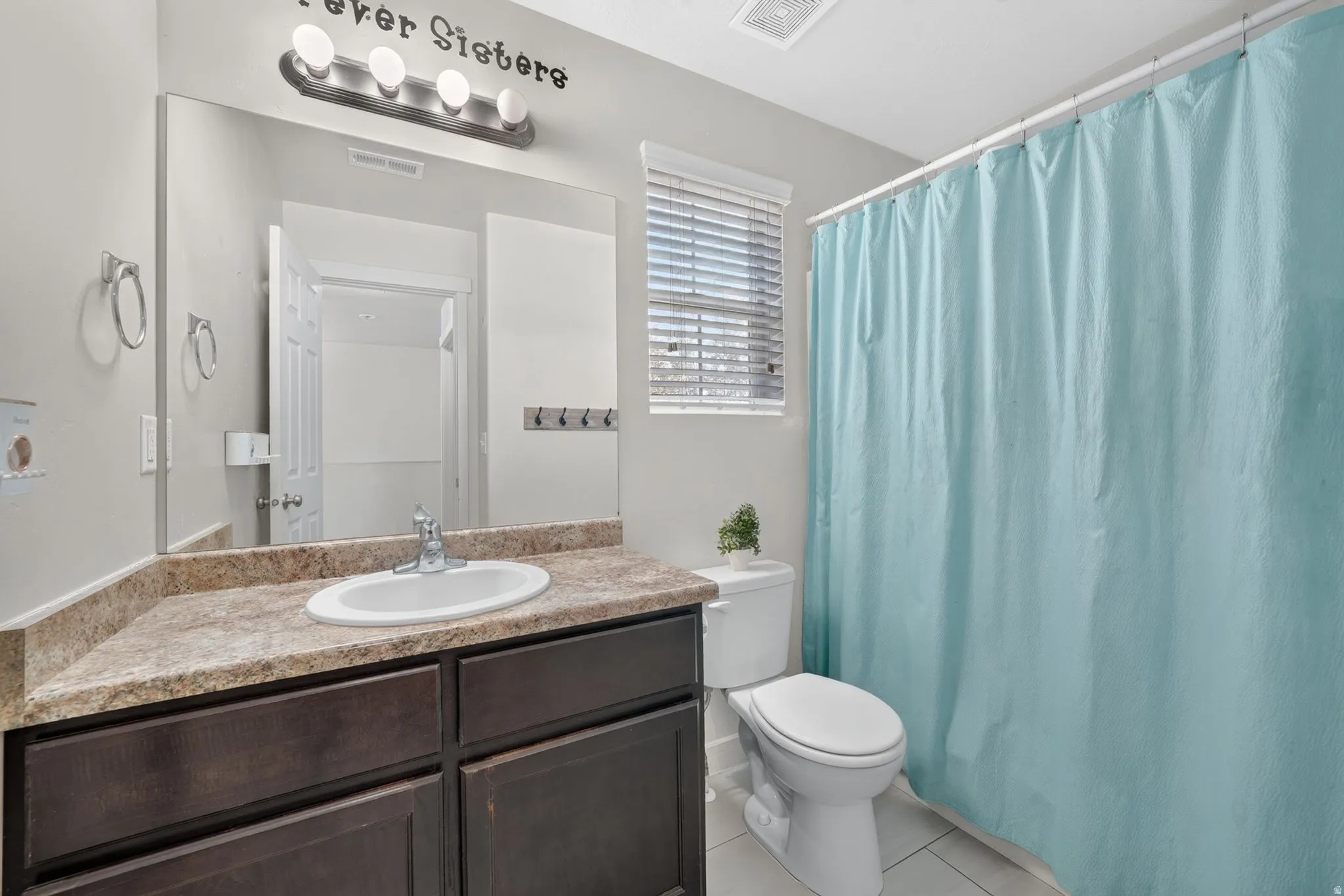 Bathroom featuring a single vanity with an integrated sink, dark wood-finish cabinetry, and a light-toned countertop