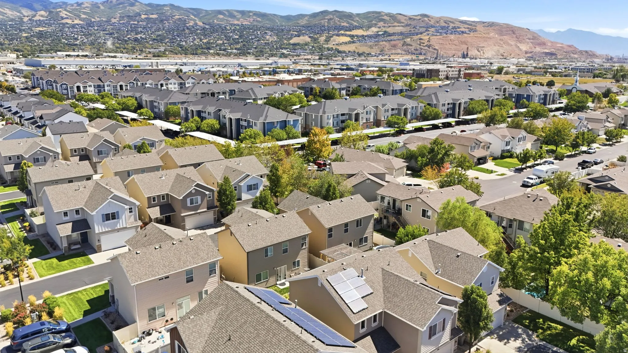 Residential community with numerous detached homes, solar panel installations, and paved streets