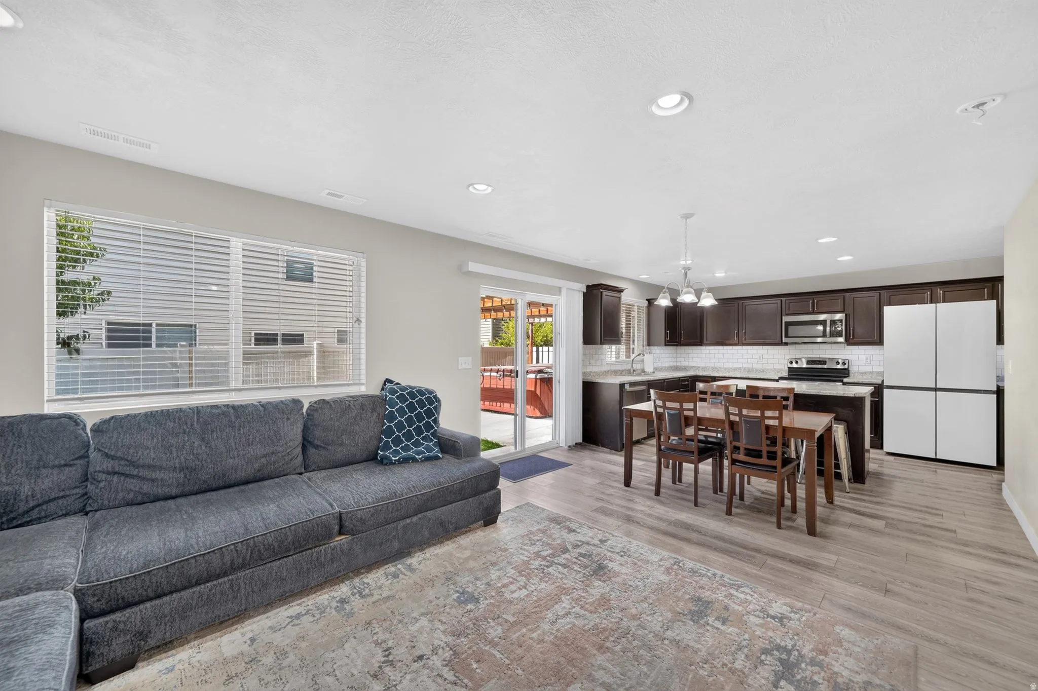 Open concept living area featuring wood-finish flooring, recessed lighting, and a sliding glass door