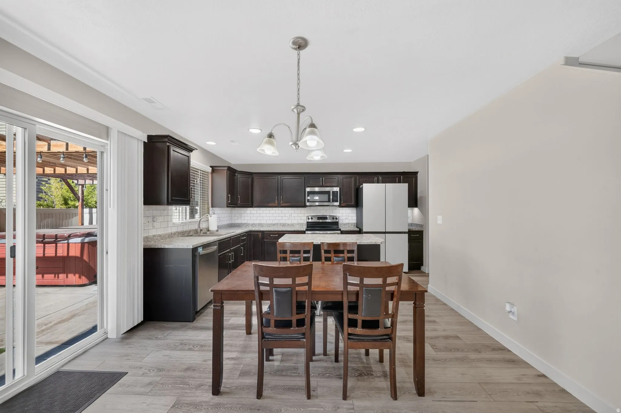 Kitchen and dining area featuring dark wood cabinetry, stainless steel appliances, a center island, and wood-finish flooring