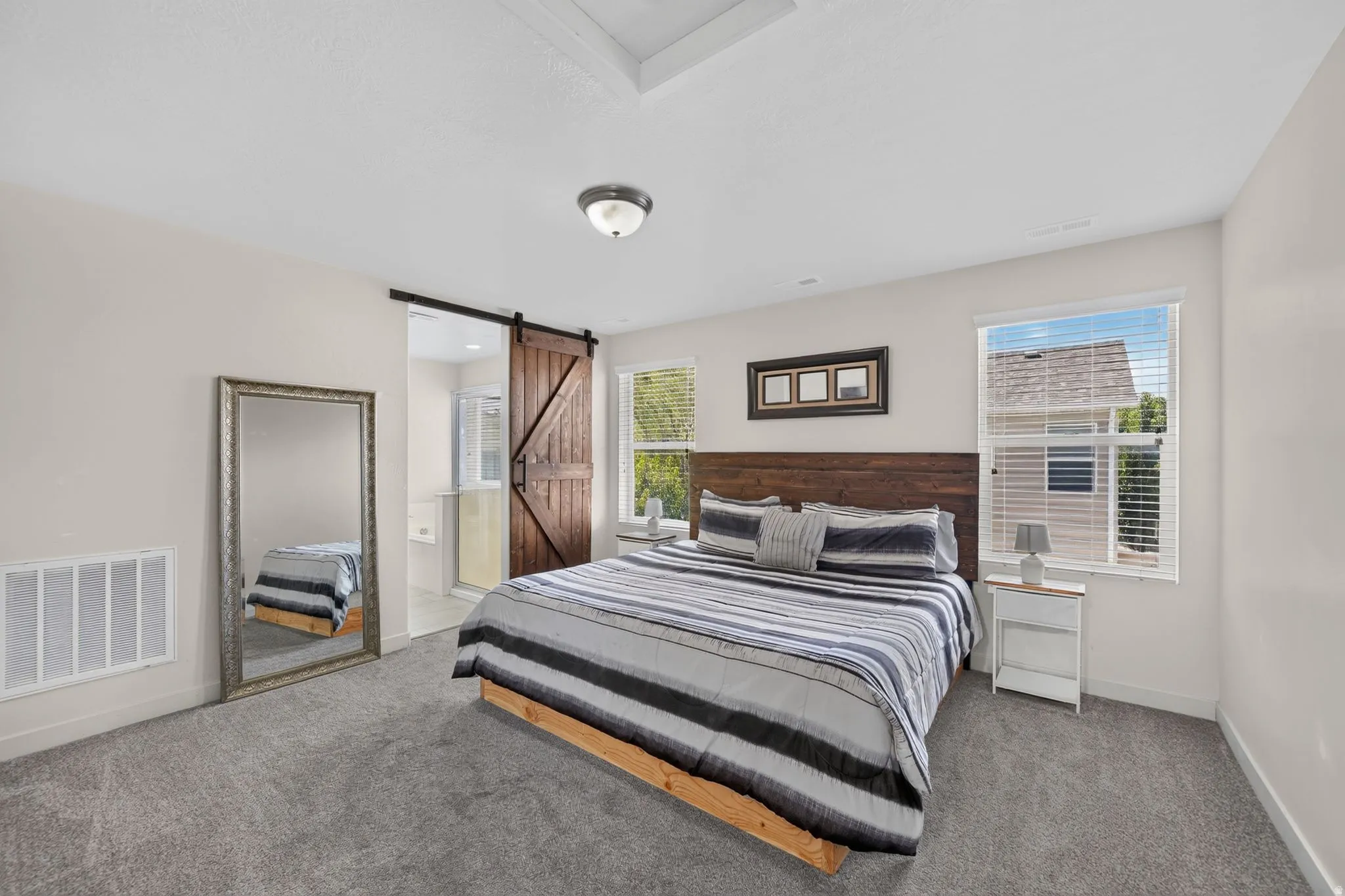 Plush carpet flooring, multiple windows, recessed ceiling light, and a wooden barn door
