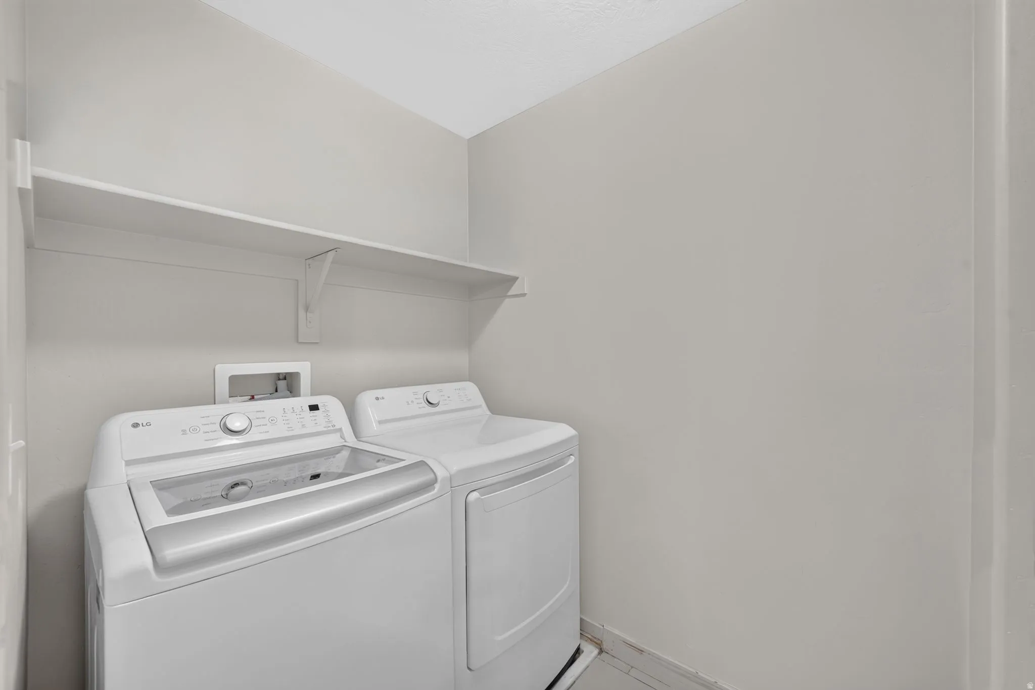 Laundry area with wall-mounted shelving and washer/dryer hookups