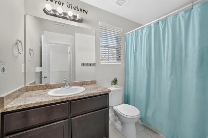 Bathroom featuring a single vanity with an integrated sink, dark wood-finish cabinetry, and a light-toned countertop
